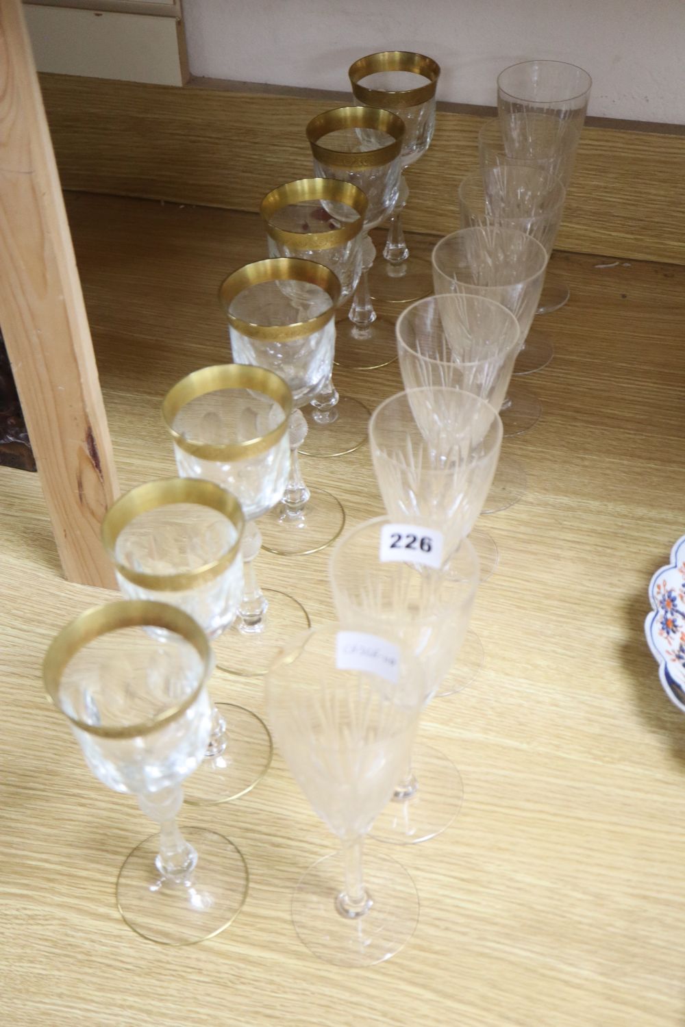 A set of seven gilt rimmed wine glasses and eight glass flutes